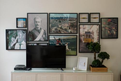 a flat screen tv sitting on a dresser with pictures on the wall at Fanqueiros 204 - Old Town in Lisbon