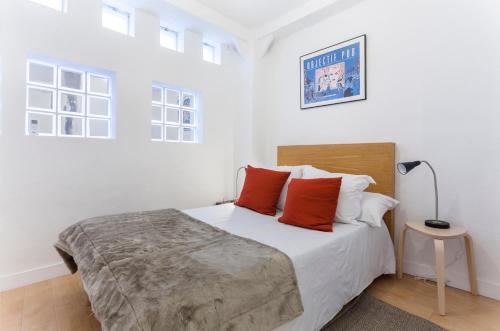 Un dormitorio blanco con una cama grande con almohadas rojas en MIT House Chueca V en Madrid, en Madrid