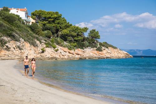 a man and a woman walking on the beach at Lu' Hotel Maladroxia in SantʼAntìoco
