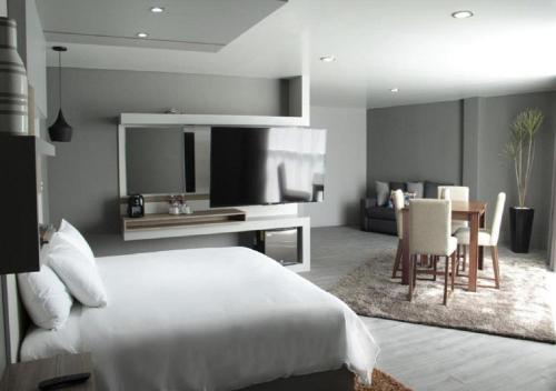 - une chambre avec un lit blanc et une salle à manger dans l'établissement ESDUMA HK HOTEL Pachuca, à Pachuca
