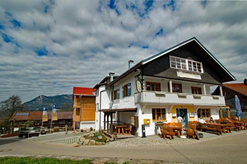 un bâtiment blanc avec des tables et des chaises devant lui dans l'établissement Berggasthof Sonne Allgäu, à Sonthofen