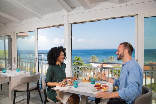 a man and a woman sitting at a table eating food at Lu' Hotel Maladroxia in SantʼAntìoco