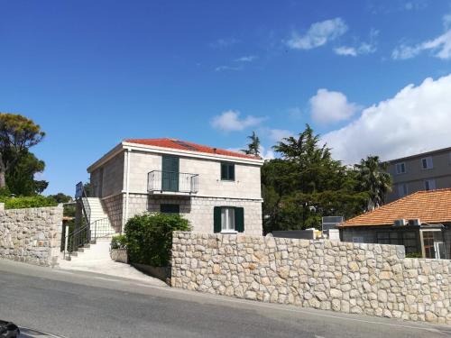 a white house behind a stone wall at Apartments Corner in Dubrovnik