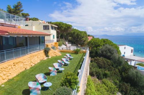 a row of chairs and umbrellas on the side of a house at Lu' Hotel Maladroxia in SantʼAntìoco