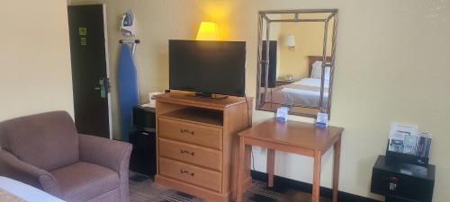 a bedroom with a tv and a chair and a mirror at Travelodge by Wyndham Airport Platte City in Platte City
