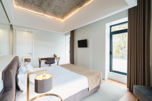 a bedroom with a bed and a desk and a window at Borralha Hotel, Restaurante & Spa in Vila Real