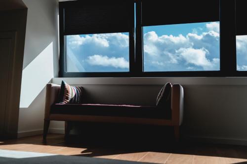 a bench in front of a window with clouds in the sky at Borralha Hotel, Restaurante & Spa in Vila Real