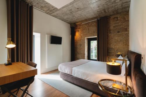a bedroom with a bed and a desk and a table at Borralha Hotel, Restaurante & Spa in Vila Real