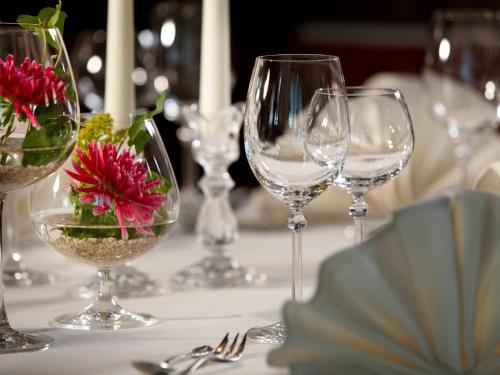 a table with wine glasses and flowers on it at Landhotel Halbfas-Alterauge in Drolshagen