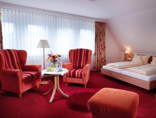 a hotel room with a bed and two chairs at Landhotel Halbfas-Alterauge in Drolshagen