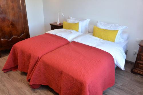 a bed with a red and white blanket and yellow pillows at Les magnolias en Alsace - meublé de tourisme 3 étoiles in Barembach