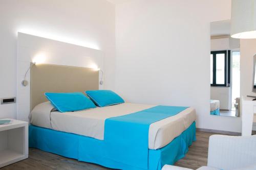 a bedroom with a large bed with blue pillows at Lu' Hotel Maladroxia in SantʼAntìoco