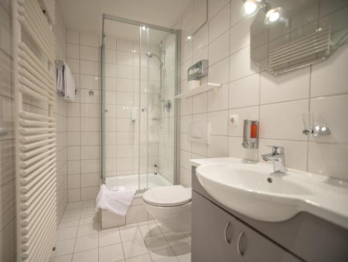 a bathroom with a sink and a toilet and a shower at Hotel am Hachinger Bach by Blattl in Neubiberg