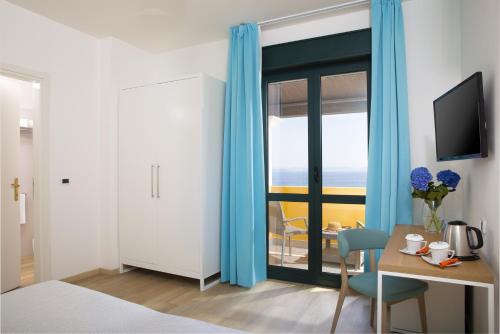 a bedroom with blue curtains and a table with a chair at Lu' Hotel Maladroxia in SantʼAntìoco