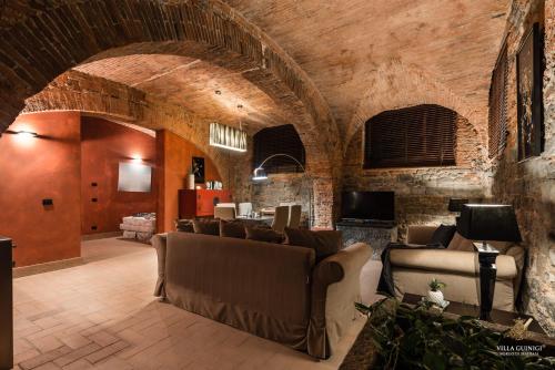 a living room with couches and a stone wall at Villa Guinigi Dimora di Epoca Exclusive Residence & Pool in Lucca