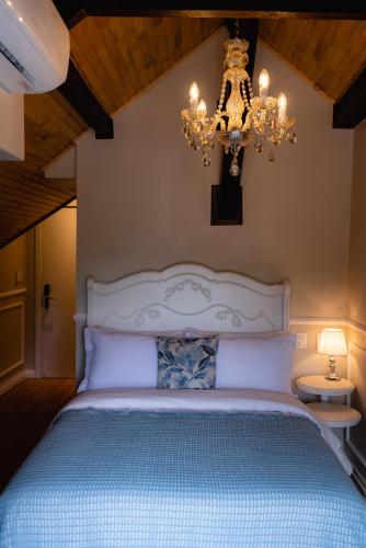 a bedroom with a large bed with a chandelier at Castelo Boutique Hotel in Fraiburgo