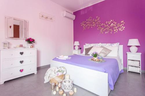 Dormitorio púrpura con cama blanca y pared púrpura en B&B La Corte della Nonna, en Samarate