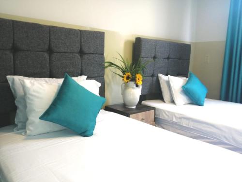 Hotel Brickell في ليما: غرفة نوم بسريرين مع وسائد زرقاء وبيضاء