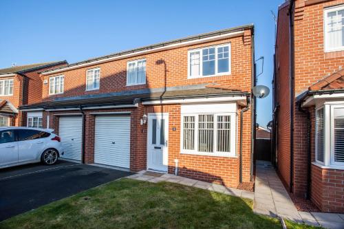 a brick house with a car parked in the driveway at Wilton Lodge in Redcar