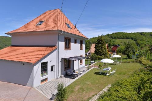a white house with an orange roof and a yard at Les magnolias en Alsace - meublé de tourisme 3 étoiles in Barembach