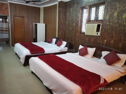 two beds in a hotel room with red and white sheets at Hotel Aarti Darshan in Haridwār
