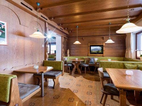 a restaurant with wooden walls and tables and green booths at Tirol Appartements Schwaiger in Niederndorf