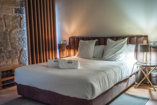 a bedroom with a large bed with white sheets and pillows at Borralha Hotel, Restaurante & Spa in Vila Real