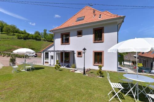 a house with a yard with chairs and umbrellas at Les magnolias en Alsace - meublé de tourisme 3 étoiles in Barembach