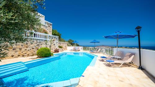 a swimming pool with chairs and an umbrella at Ilios Village in Stalos