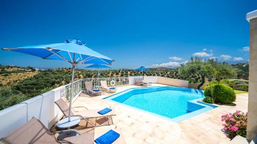 a swimming pool with two chairs and an umbrella at Ilios Village in Stalos