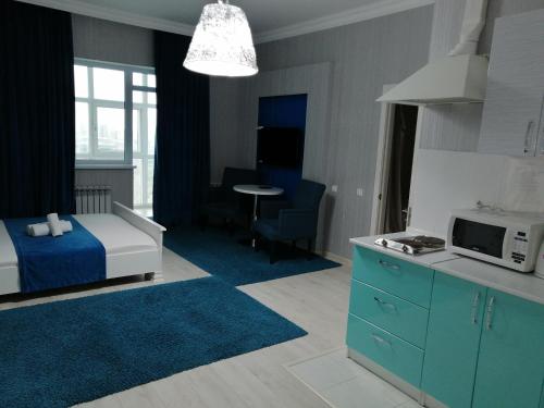 ein Schlafzimmer mit einem Bett und eine Küche mit einer Mikrowelle in der Unterkunft Апартаменты на набережной 15 этаж in Astana