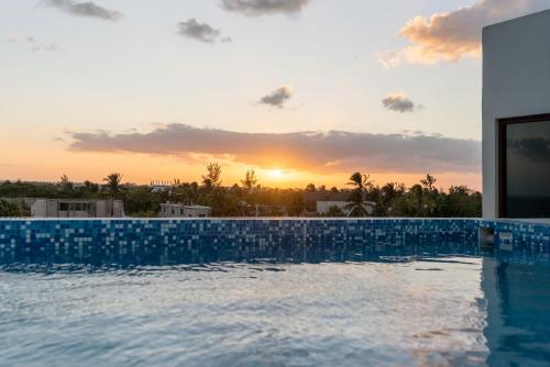 a swimming pool with the sunset in the background at Hotel MAYARI Holbox in Holbox Island