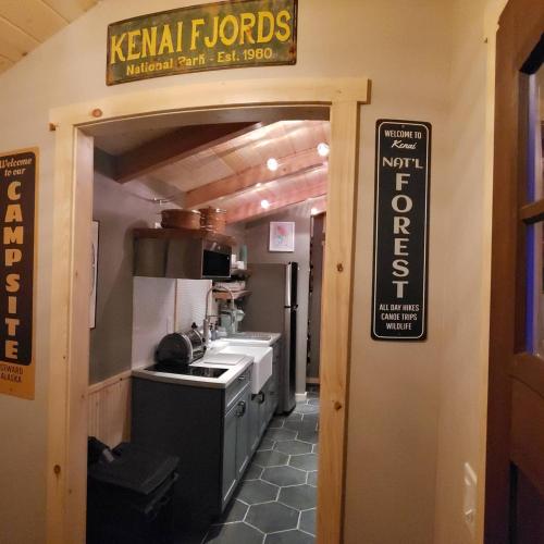 a kitchen with a sign that reads kennettslordsnational art eat at Entire Tiny Home close to cruise ship terminal Alaska Railroad and downtown Seward in Seward