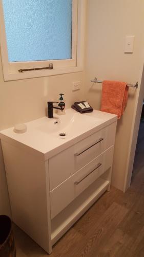 a bathroom with a white sink and a mirror at Jacks place in Moeraki
