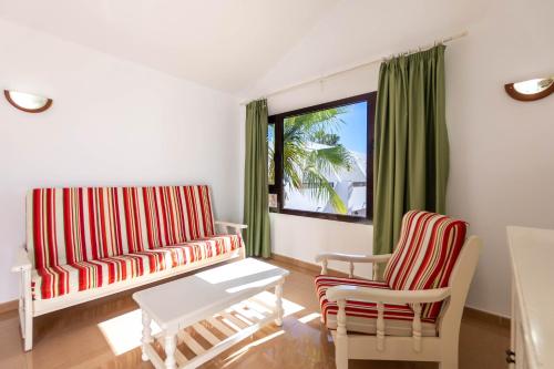 卡门港Apartamentos Flamingo的客厅里有一张沙发和两把椅子