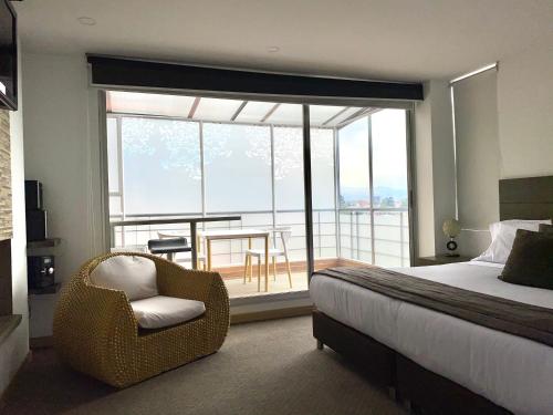 sypialnia z łóżkiem i krzesłem oraz balkon w obiekcie Hotel Apartamentos Regency La Feria w mieście Bogota