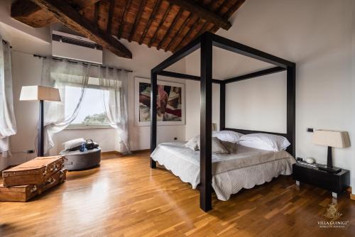 a bedroom with a large black canopy bed and wooden floors at Villa Guinigi Dimora di Epoca Exclusive Residence & Pool in Lucca