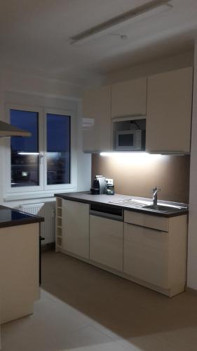 a kitchen with white cabinets and a sink and two windows at Appartment Zentrum Wels in Wels