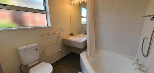 a bathroom with a toilet and a sink and a tub at Rosewood Court Motel in Christchurch