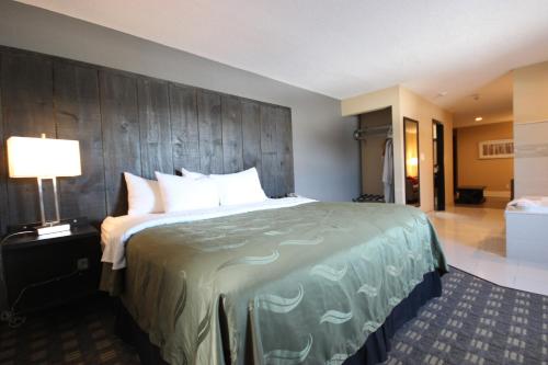 a large bed in a hotel room with a lamp at Quality Inn Bracebridge in Bracebridge