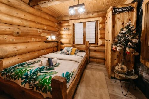a bedroom in a log cabin with a bed and a christmas tree at Szepit in Lutowiska