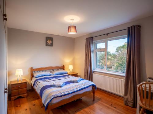 a bedroom with a bed and a large window at Sea view cottage in Tully Cross