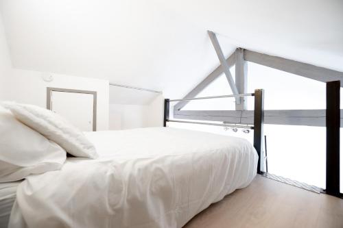 Cette chambre comprend un lit blanc et une grande fenêtre. dans l'établissement Le Petit Angoumoisin, à Angoulême