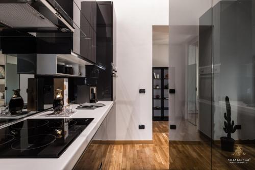 a kitchen with white counters and black appliances at Villa Guinigi Dimora di Epoca Exclusive Residence & Pool in Lucca