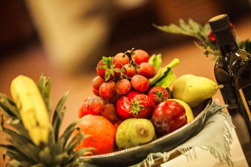 a bowl of fruit and a bottle of wine at Hotel Quadrifoglio in Cagliari