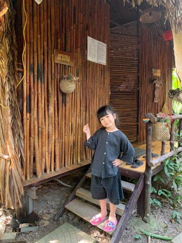 a young boy standing on a wooden stairs in front of a wall at Saigon Garden Homestay in Ho Chi Minh City