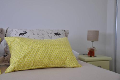 a bedroom with a bed with a yellow pillow and a lamp at La Amada in Puerto Madryn