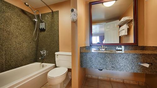 a bathroom with a tub and a toilet and a sink at Best Western Pier Point Inn in Florence
