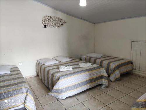 two beds in a room with white walls at Pousada das Letras in São Thomé das Letras
