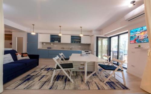 sala de estar con mesa blanca y sofá azul en Portami Al Mare - apartament, terasă & curte, en Mamaia Nord – Năvodari